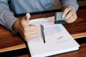 businessman Hand notary public hand ink appoval stamper Stamping seal On Approved Contract Form